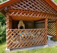 A gazebo with a wooden lattice and an outdoor grill in the garden by the family house.