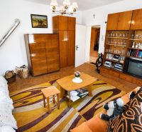 Living room in a family house with a carpet, furniture, television, and a stove.