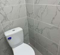A restroom with marble tiles in commercial spaces, gray floor.