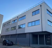 Commercial premises in Levice at Komenského 2A 2B with glass windows and a parked car.