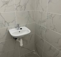 A sink and tiles in commercial premises with a marble pattern.