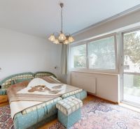 Bedroom in a 3-room apartment with a large window, colorful carpet, and double bed.