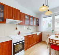 A kitchen with wooden decor and a dining area with chairs.