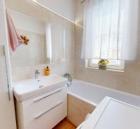 A bathroom in a 3-room apartment with a bathtub, a sink, and storage space.