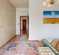 Bedroom in a 3-room apartment with a wooden decor floor, carpet, and a painting on the wall.