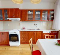 A kitchen in a 3-room apartment with wooden cabinets, a stove, and a floor with a wooden decor.