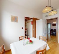 A kitchen in a 3-room apartment with a wooden decor floor, a white table, and chairs.