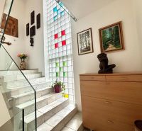 Nicely lit stairs with decorations, artworks, and flowers in a 3-room apartment.