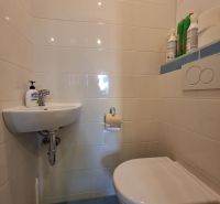 A toilet with a sink in a 3-room apartment has light tiles.