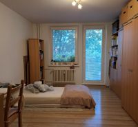 A room in a 3-room apartment with a bed, shelves, and a floor with a wood decor.