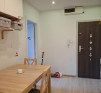 Dining room in a 3-room apartment with a wooden decor floor and a wooden table.
