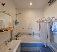 A bathroom in a 3-room apartment with a bathtub, a mirrored cabinet, and tiles.
