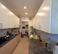 A kitchen in a 3-room apartment with white cabinets and a wood-patterned floor.