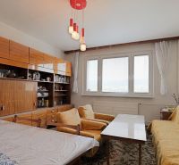 Living room in a 2-room apartment with carpet patterns and yellow sofas.