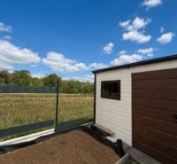 The garden of a family house in Kendice with a view of the surrounding nature and a cloudless sky.