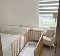 Children's room with a wooden crib, light furniture, and an armchair in a family house.