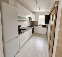 A kitchen in a family house with white furniture and a light floor with a wooden decor.