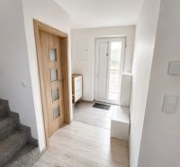 Interior of a family house with a wooden decor floor, staircase, and wooden doors.