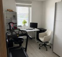 Home office with a treadmill, desk, and shelving unit.