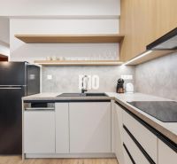A kitchen in a studio apartment with a wood-patterned floor and a black refrigerator.