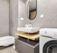 Bathroom in a studio apartment with a modern washing machine and gray tiles.