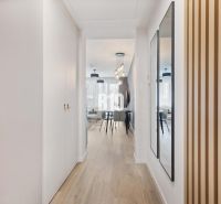 A hallway with a wooden decor floor, a mirror, and an entrance to the living area.