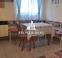 Dining room in a family house with a stove, table, and chairs with cushions.