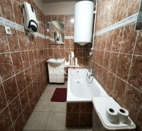 A bathroom in a family house with brown tiles and a bathtub.