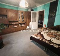 A room in a family house with wooden furniture, green walls, and a comfortable bed.