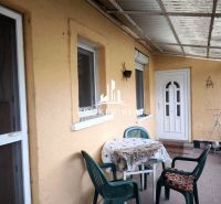 The terrace of a family house in Bódvaszilas with a table and plastic chairs on a paved floor.