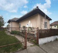 A family house in Bódvaszilas surrounded by a garden, with white plaster and a fence.