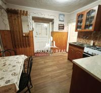 A kitchen in a family house with a wooden decor floor, a dining table, and a kitchen unit.