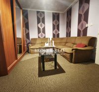 Living room in a family house with a striped sofa and colorful wallpaper.