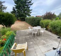 The garden of a family house in Zvončín with a paved terrace, chairs, and green plants.