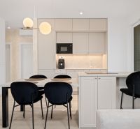 A kitchen in a 3-room apartment with a dining table and black chairs.