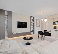 A bright living space in a 3-room apartment with a wooden decor floor and a kitchen unit.