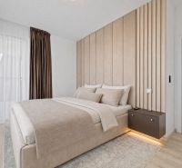 Elegant bedroom with neutral colors and wood-patterned flooring in a three-room apartment.