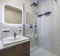 A bathroom in a 3-room apartment with a shower, mirror, and sink.