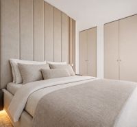 A bedroom in a three-room apartment with a comfortable bed and built-in wardrobes in neutral colors.