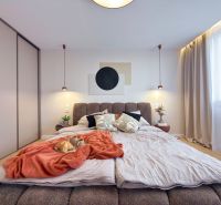 A bedroom in a three-room apartment with a bed, curtains, and a wardrobe; a floor with a wooden decor.