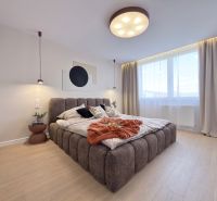 A bright bedroom with a large bed and a wooden decor floor in a 3-room apartment.