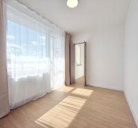 A bright room with curtains and a wooden decor floor in a 3-room apartment.