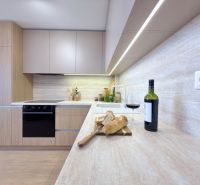 A kitchen in a 3-room apartment with wine, bread, and a wooden decor floor.