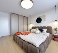 A bedroom in a 3-room apartment with a large bed and a floor with a wooden decor.