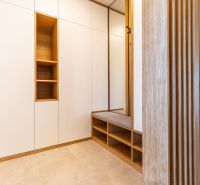 A hallway in a family house with furniture, seating, and wooden wall paneling.