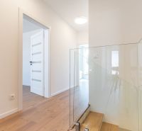 Interior of a family house with a wooden decor floor and glass railing by the stairs.