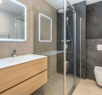 Bathroom with wooden furniture, a shower cabin, and a large mirror in a family house.