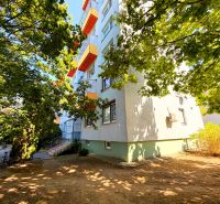 An apartment building with colorful balconies on Lúky Street in Vráble, surrounded by trees.
