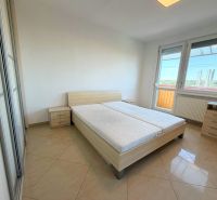 Bright bedroom in a one-room apartment with a bed, wardrobe, and balcony.