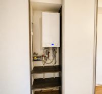 Built-in wardrobe with a boiler in a 3-room apartment, floor with wood decor.
